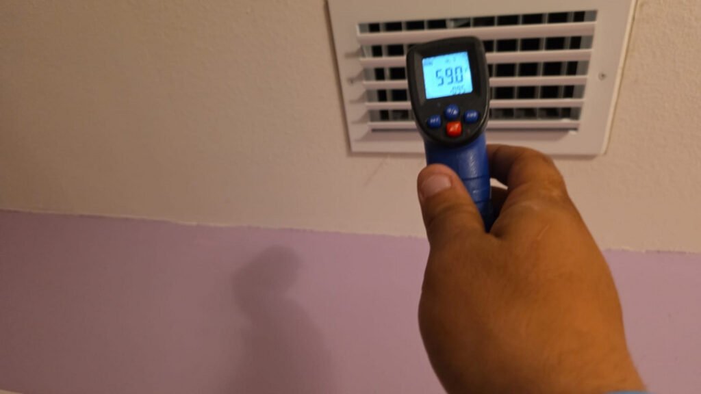From one of our recent jobs: measuring air temperature with a digital thermometer near a vent indicating potential heating or cooling system checks.