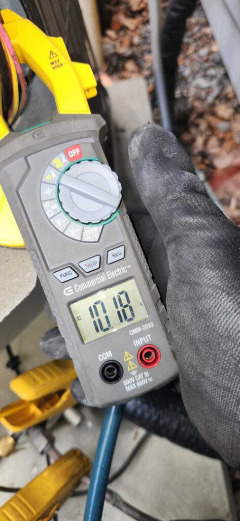 measuring electrical current using a multimeter with gloves on and surrounding tools visible in the background