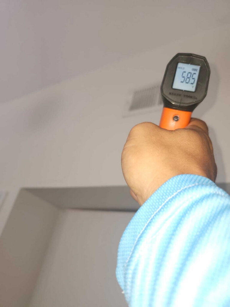 measuring temperature in a room with an infrared thermometer showing a reading of fifty eight point five degrees