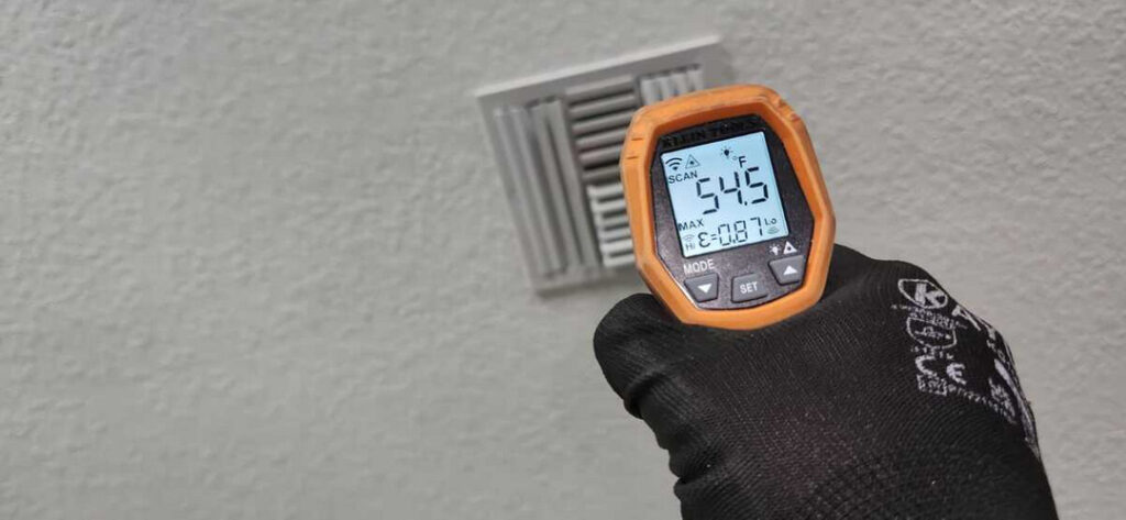 measuring the temperature of an air vent using a thermal gun in a residential setting
