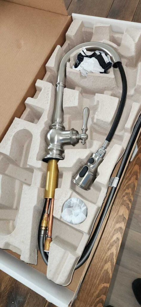 metal faucet and parts for plumbing installation in protective packaging on a wooden surface
