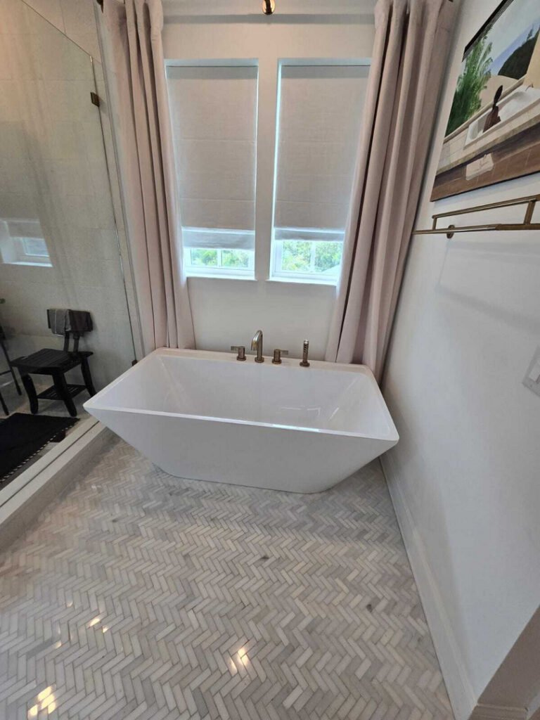 modern bathroom featuring a freestanding bathtub with a stylish design and herringbone patterned tile flooring