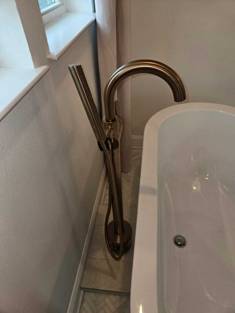 modern bathtub faucet installation with a handheld shower attachment and a sleek design near a window and tiled floor