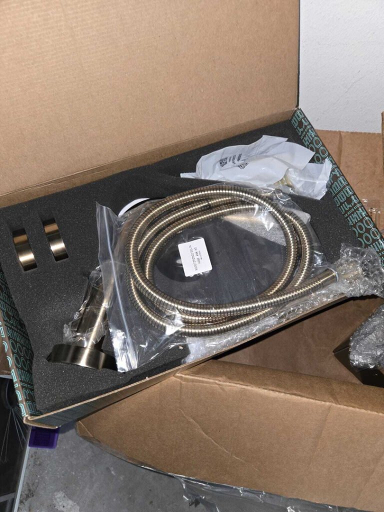 new plumbing fixture parts packaged in a box including a hose and mounting hardware for installation or replacement