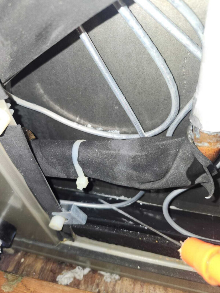 pipes and wires connected to a dark surface indicating possible plumbing or heating system installation or repair work