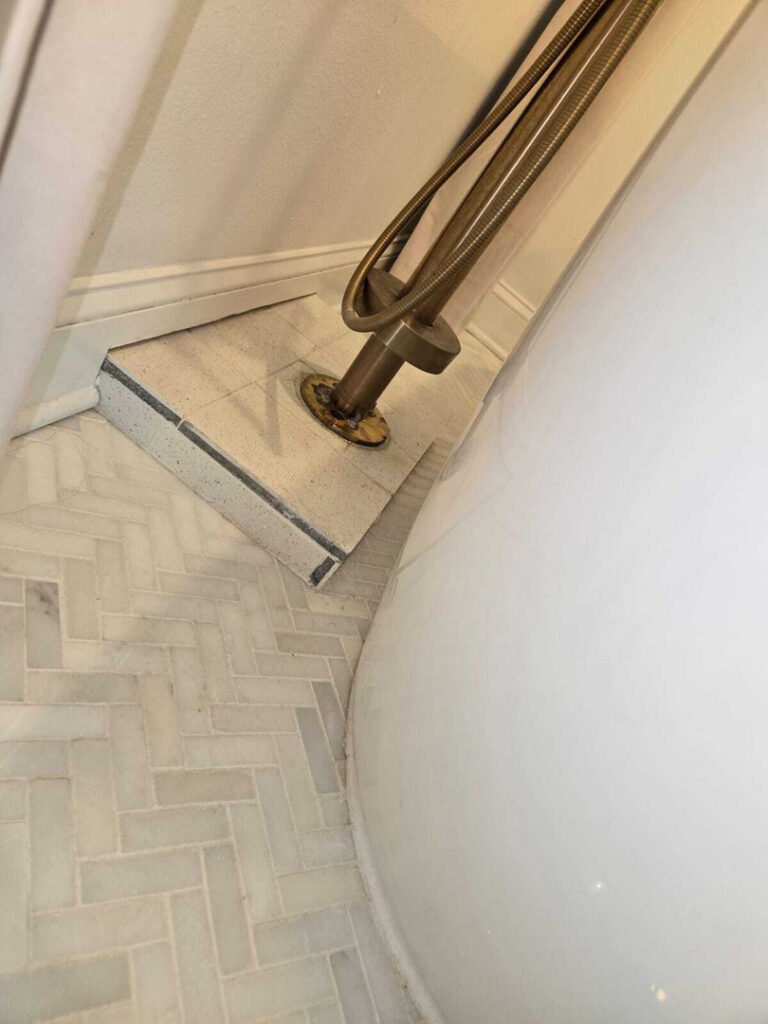 plumbing installation with a shower drain and decorative tile floor visible in the corner of a bathroom setting