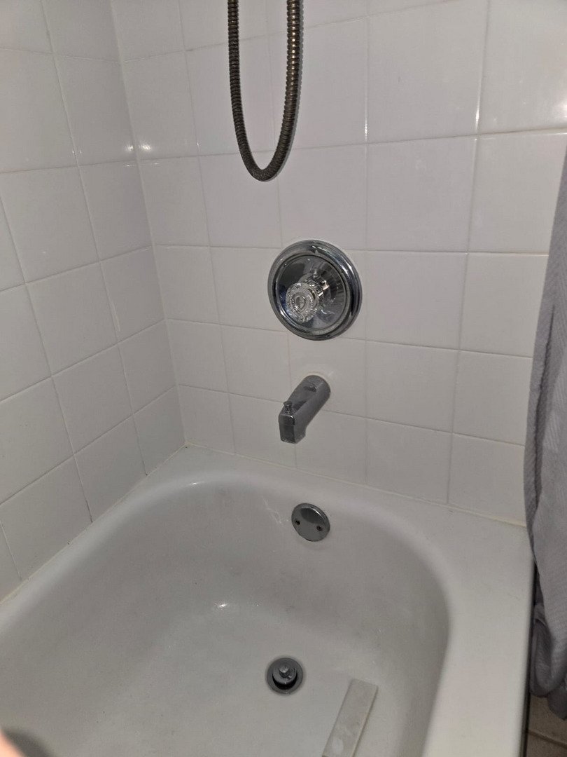 plumbing installation with a shower faucet handle and wall tiles in a bathroom setting