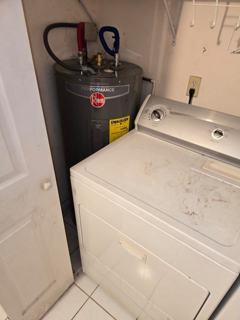 plumbing service installing a rheem water heater next to a washing machine in a laundry area with visible utility connections
