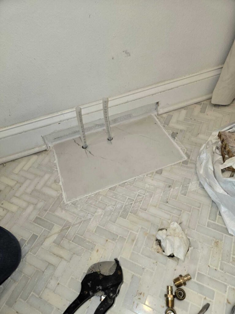 plumbing work being done on floor pipes with tools and materials nearby including adjustable pliers and metal fittings
