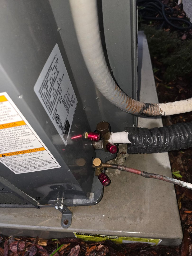repairing an outdoor air conditioning unit with copper tubing and valves visible along with maintenance tags