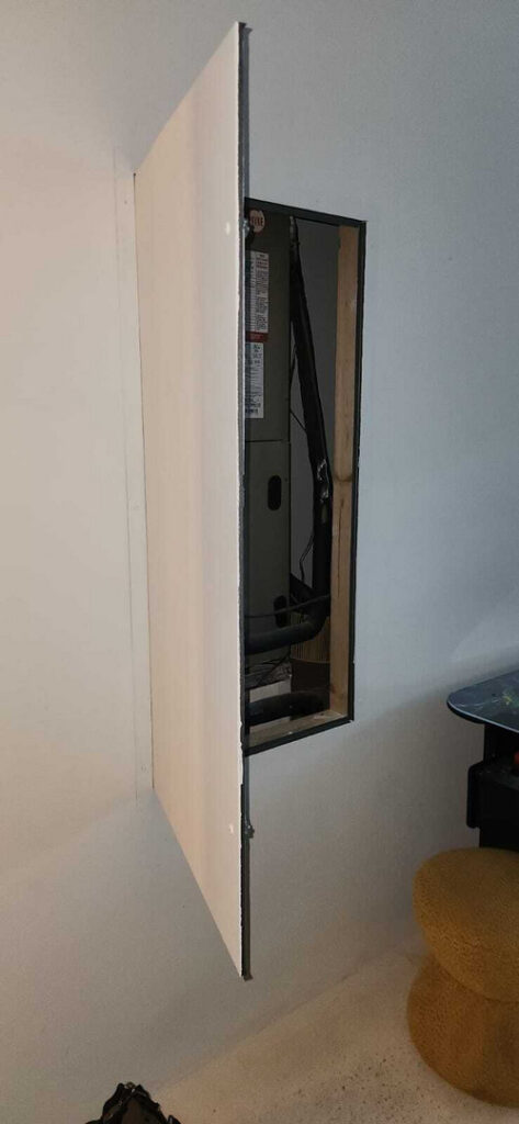 service panel access being created for maintenance with tools and equipment visible in a residential setting