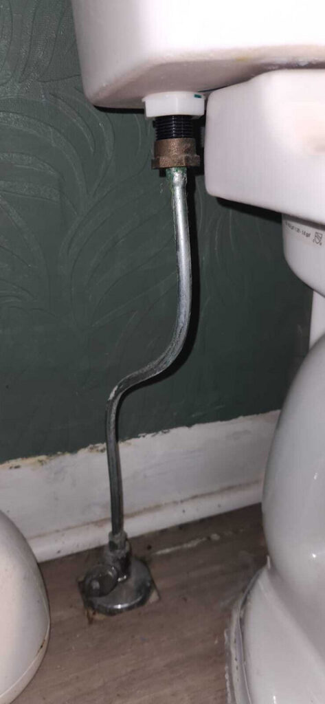 toilet plumbing installation with tank connection and shutoff valve visible on the floor near the toilet base
