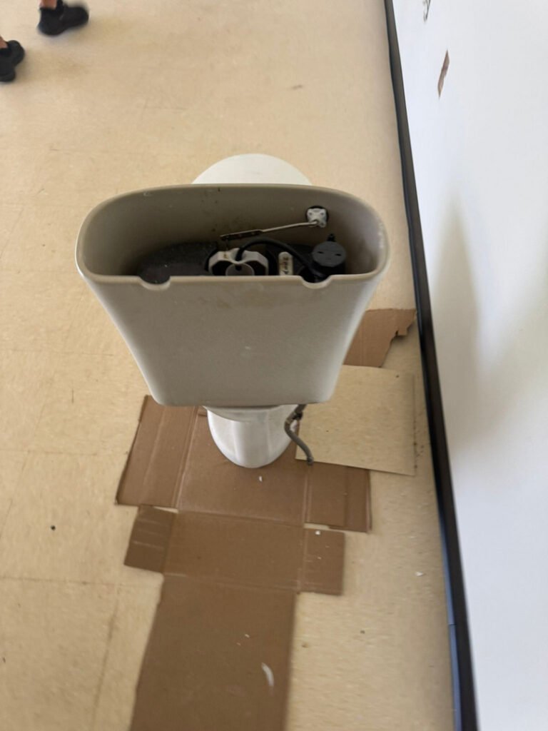 From one of our recent jobs: toilet tank being serviced or repaired with tools and cardboard for protection on the floor.