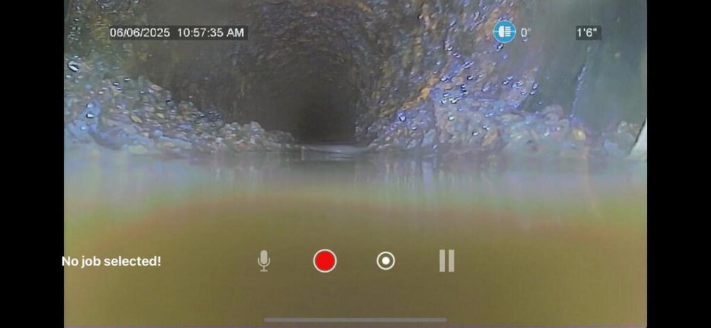 underwater view of a pipe showing potential blockage or buildup with sediment along the walls and cloudy water visible