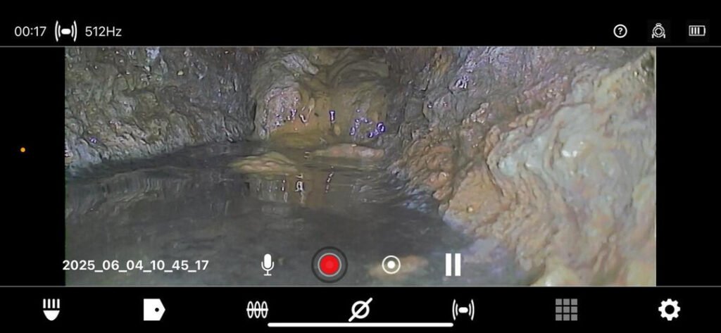 video inspection of a drain showing water flow and pipe condition with visible buildup and possibly debris present