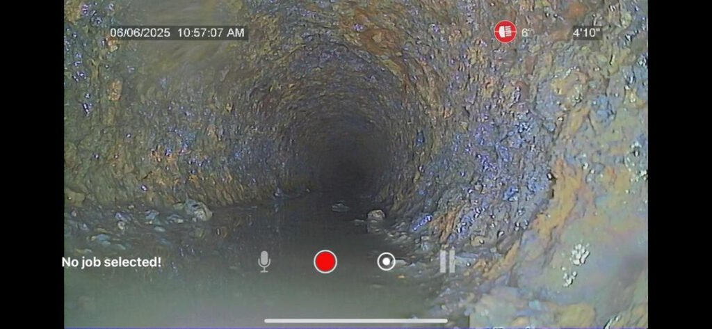 video inspection of a plumbing pipe showing buildup debris and potential blockages in a dark cylindrical space