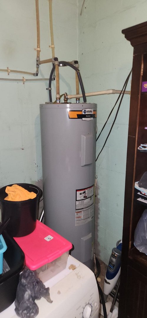 water heater installation in a basement with cleaning supplies and storage containers nearby
