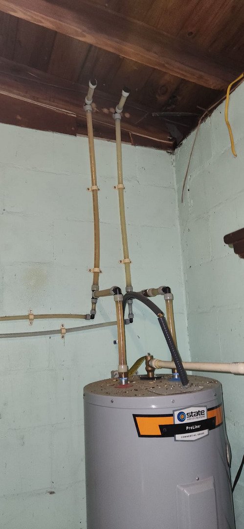 water heater installation with multiple pipes and fittings connected to a tank in a basement setting