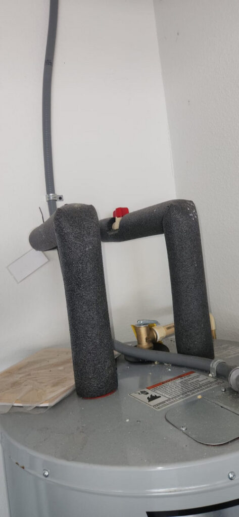 water heater with insulation on pipes and a valve visible on top likely part of maintenance or inspection service